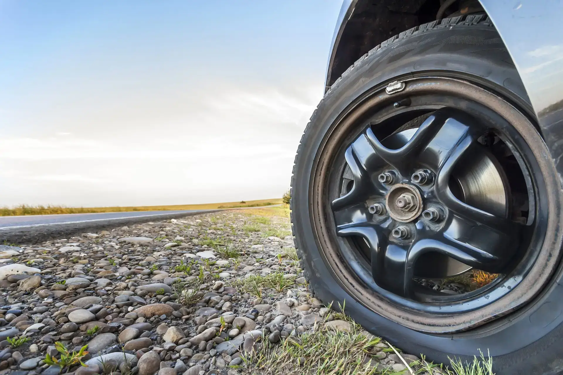 close-up-of-flat-tire-on-a-car-on-gravel-road-2024-12-06-04-01-57-utc-scaled