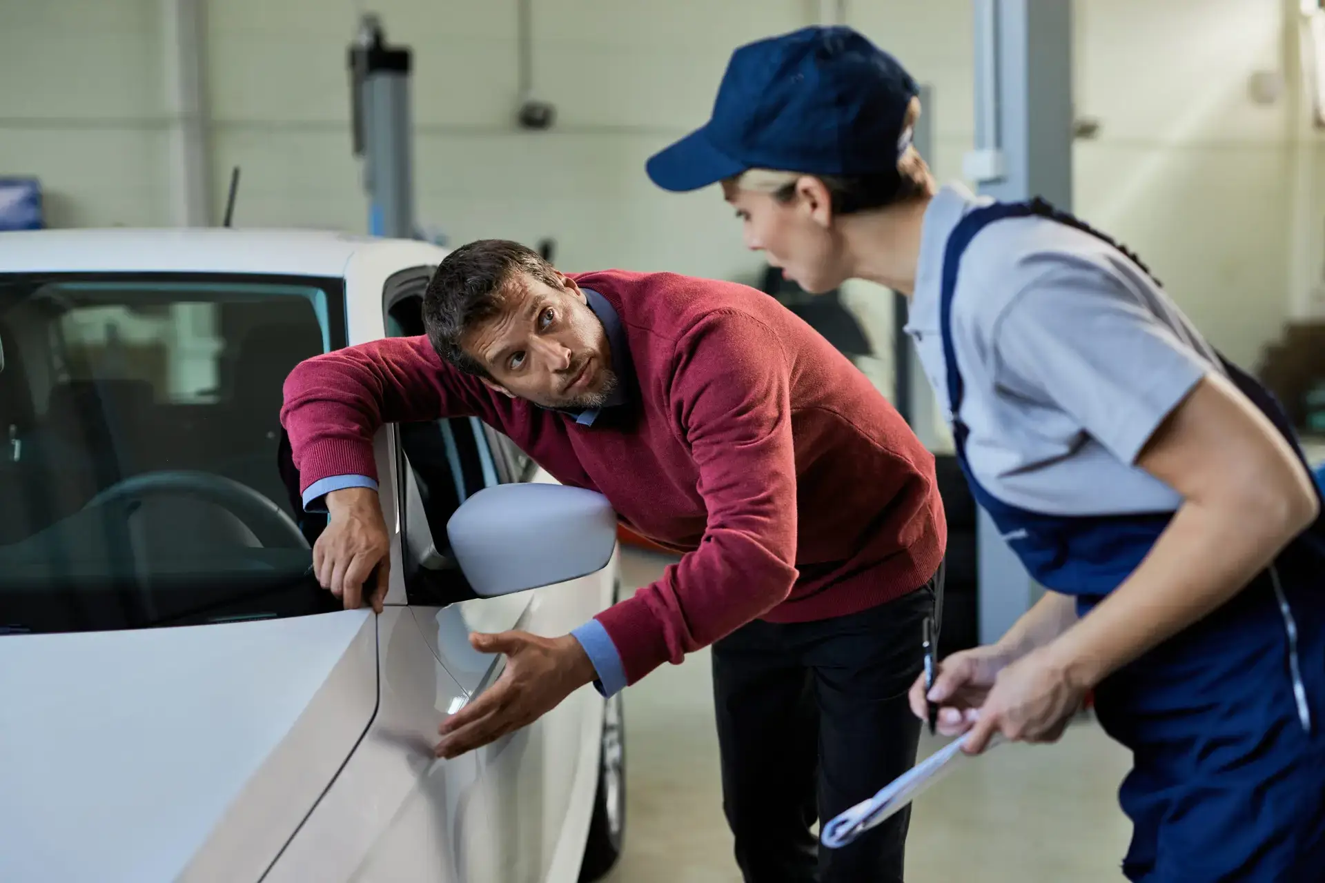 male-customer-talking-to-auto-repairwoman-while-ex-2023-11-27-05-33-51-utc-scaled